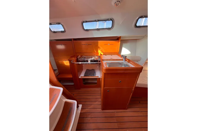 Slide: The Image of 2007 Beneteau First 10R yacht interior with wooden cabinetry and compact kitchen area. - 53