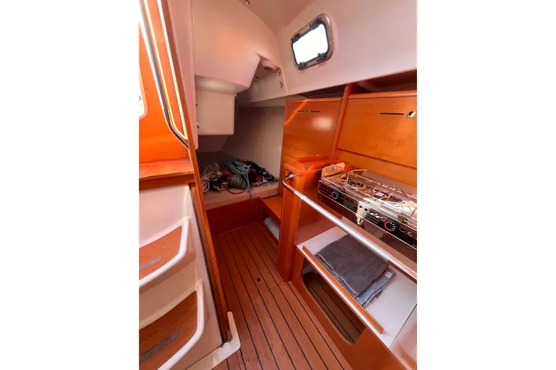 Slide: The Image of Interior of 2007 Beneteau First 10R sailboat with wooden cabinetry and compact kitchen. - 54