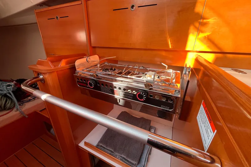 Slide: The Image of 2007 Beneteau First 10R yacht interior with compact kitchen stove and wooden cabinetry. - 58