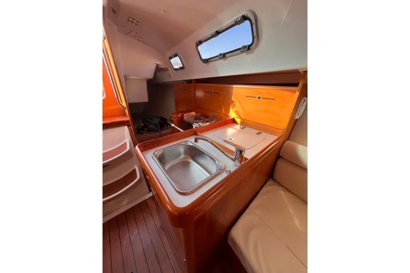 Slide: The Image of Interior of 2007 Beneteau First 10R yacht, featuring a compact kitchen with sink and stove. - 62