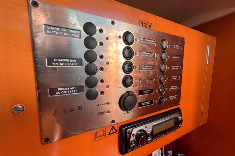 Slide: The Image of Control panel of a 2007 Beneteau First 10R sailboat with various switches and a stereo system. - 78