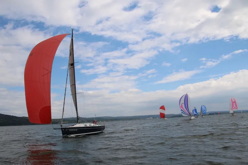 Slide: The Image of Sailboats racing on a lake, featuring a 2007 Beneteau First 10R with a red spinnaker. - 86