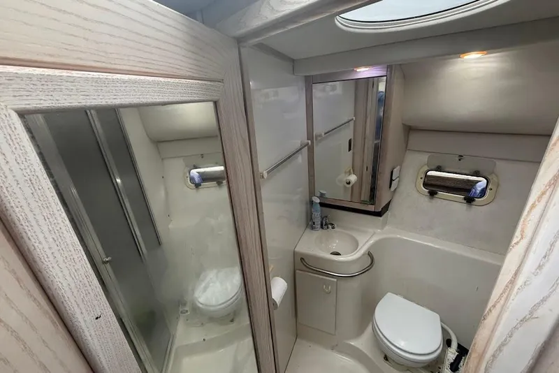 Slide: The Image of 2001 Bayliner 3258 Command Bridge bathroom with sink, toilet, mirror, and porthole window. - 9