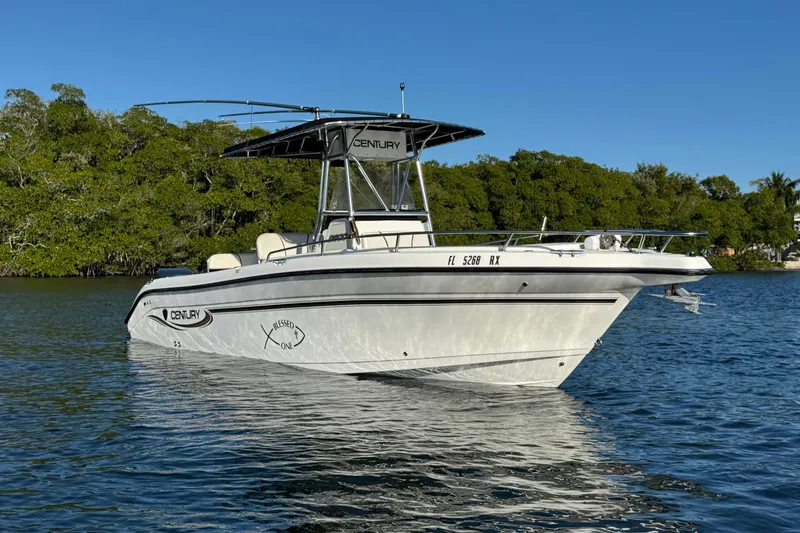 The Image of 2003 Century 2600 Center Console boat on calm water, surrounded by lush greenery. - 0