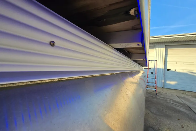 Slide: The Image of 2017 Crest Classic 230 SLC pontoon boat detail with blue lighting and garage background. - 45