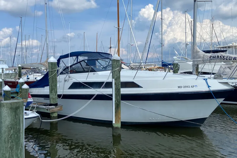 The Image of 1987 Carver 32 Montego yacht docked at marina, surrounded by sailboats under cloudy sky. - 1