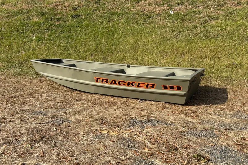 Slide: The Image of 2026 Tracker Grizzly 10 Jon boat on grassy terrain, showcasing durable design. - 11