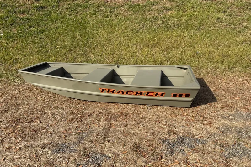 Slide: The Image of 2026 Tracker Grizzly 10 Jon boat on grassy terrain, showcasing its sturdy design. - 2