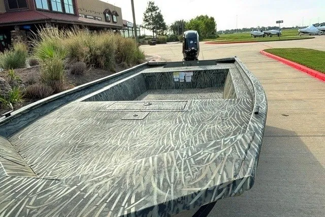 Slide: The Image of 2026 Tracker Grizzly 1754 Utility boat with camouflage design, parked outdoors. - 34