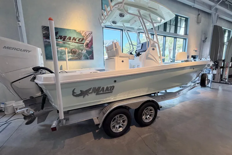 The Image of 2026 Mako 24 APEX boat on trailer in showroom, featuring Mercury engine. - 0