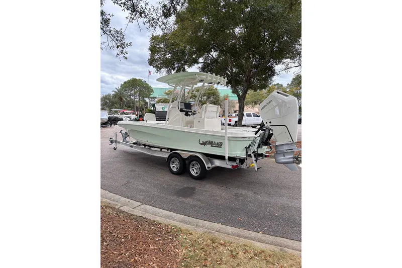 Slide: The Image of 2026 Mako 24 APEX boat on trailer, parked outdoors near trees. - 91