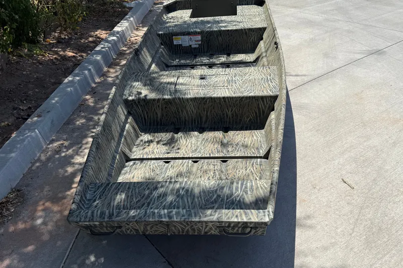 Slide: The Image of 2026 Tracker Grizzly 15 Jon boat with camouflage pattern on concrete surface. - 31