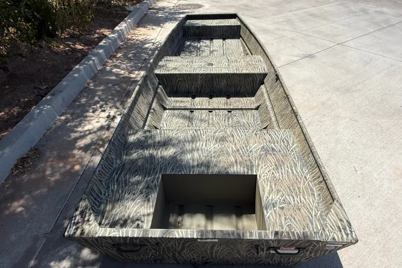 Slide: The Image of 2026 Tracker Grizzly 15 Jon boat with camouflage design on concrete surface. - 13