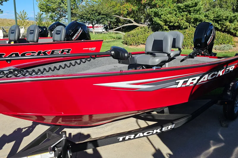 Slide: The Image of Red 2026 Tracker Super Guide V-16 T boat with Mercury engines, parked outdoors. - 17