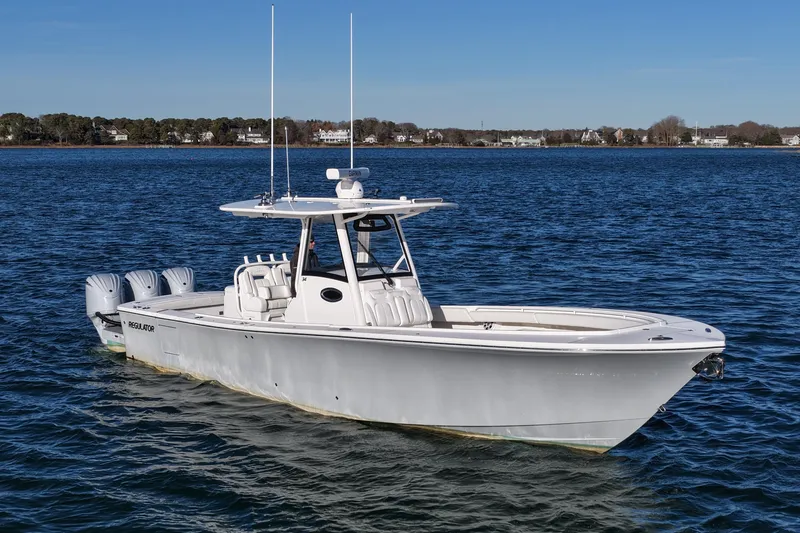 Slide: The Image of 2021 Regulator 34 boat on calm water, featuring triple outboard engines. - 12