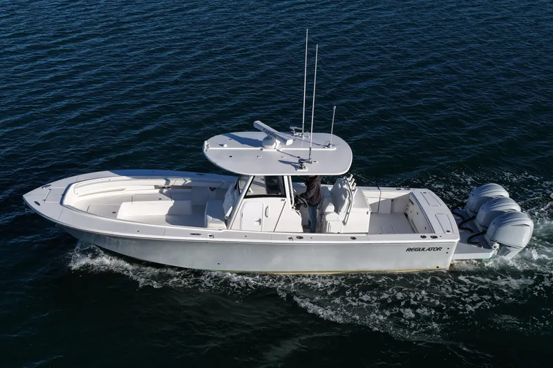 Slide: The Image of 2021 Regulator 34 boat cruising on open water, featuring triple outboard engines. - 14
