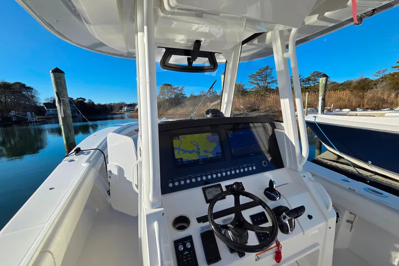 Slide: The Image of 2021 Regulator 34 boat cockpit with navigation system and steering wheel, docked by serene waters. - 23