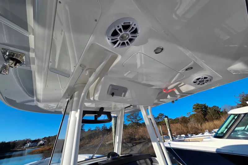 Slide: The Image of 2021 Regulator 34 boat interior with speakers and overhead console, docked by a scenic shoreline. - 25