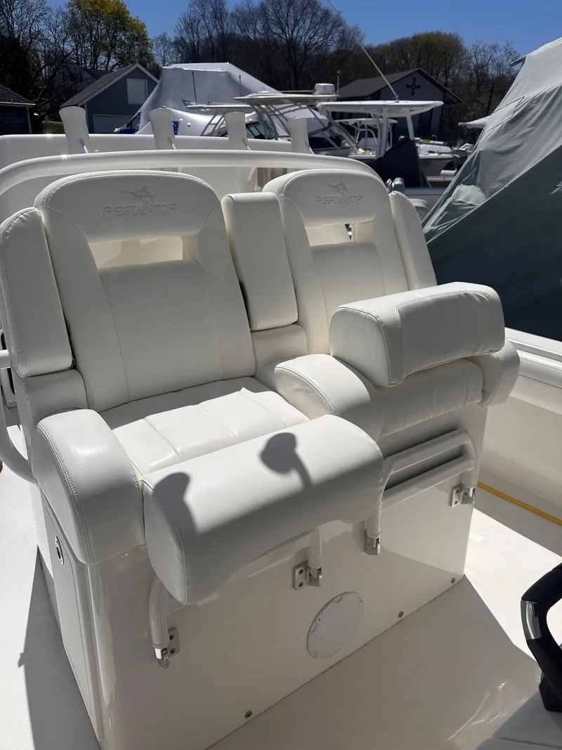 Slide: The Image of 2021 Regulator 34 boat with white cushioned seating in a marina setting. - 27