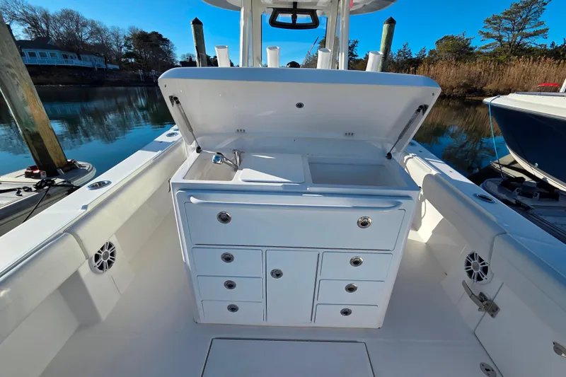 Slide: The Image of 2021 Regulator 34 boat with open storage compartment and sink, docked by calm waters. - 31
