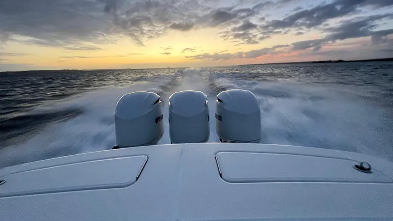 Slide: The Image of 2021 Regulator 34 boat with triple engines cruising at sunset on open water. - 39