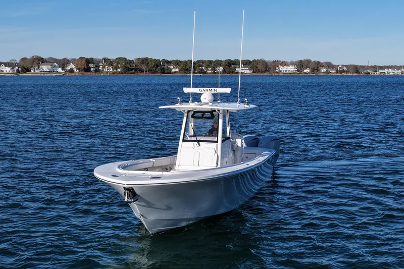 Slide: The Image of 2021 Regulator 34 boat cruising on a calm blue lake with shoreline houses. - 9