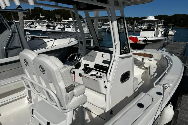 Slide: The Image of 2023 Edgewater 230CC boat interior with dual seats and control panel at marina. - 4