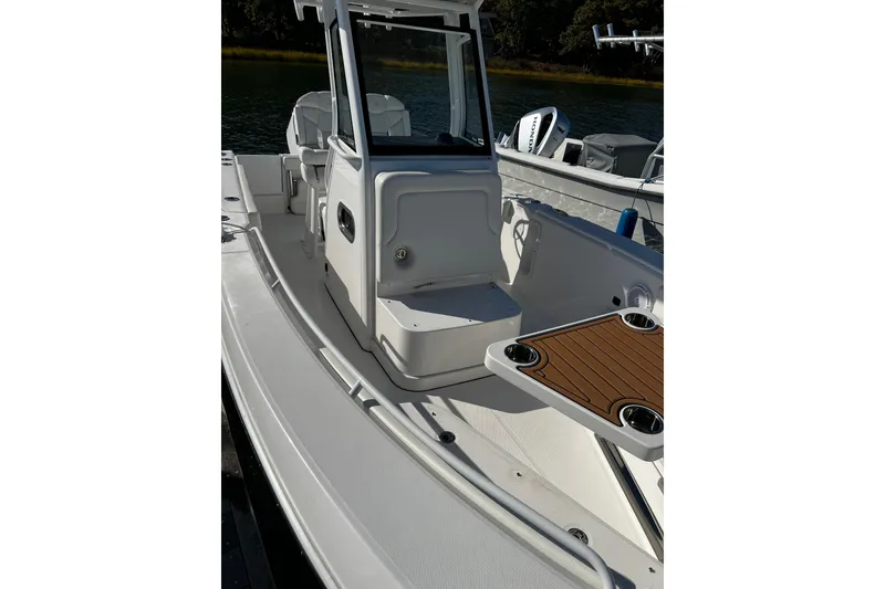 Slide: The Image of 2023 Edgewater 230CC boat interior with seating and console, docked on calm water. - 5
