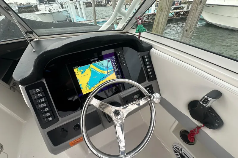 Slide: The Image of 2022 Robalo R247 Dual Console boat dashboard with navigation display and steering wheel. - 11