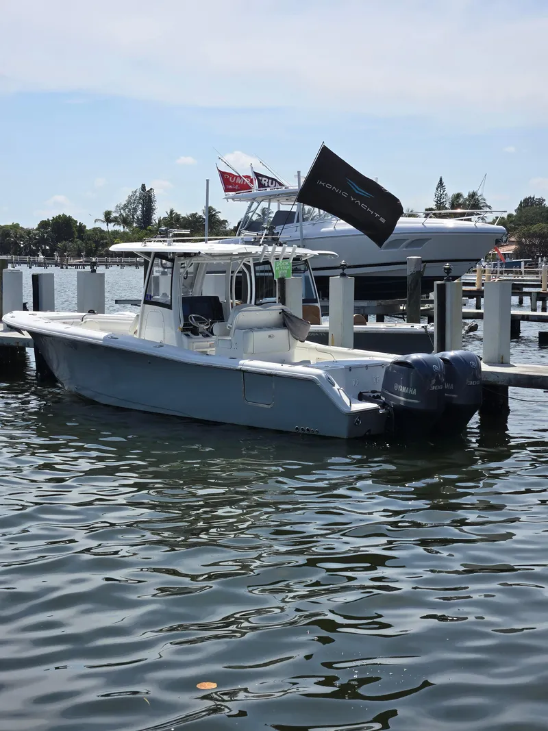 The Image of 2018 Sea Hunt Gamefish 30 boat docked with twin Yamaha engines, calm water background. - 0