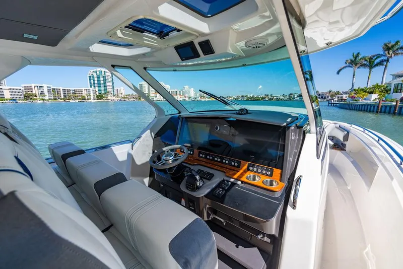 Slide: The Image of 2021 Tiara Yachts 38 LS helm with modern controls, overlooking scenic waterfront. - 16