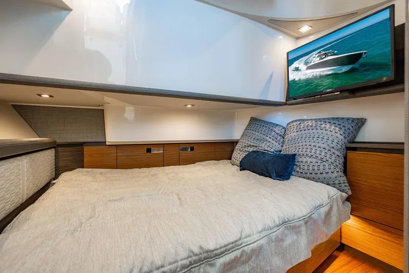 Slide: The Image of 2021 Tiara Yachts 38 LS cabin interior with bed, pillows, and wall-mounted TV. - 21