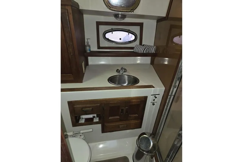 Slide: The Image of 1991 Cooper Marine Prowler boat bathroom with sink, wooden cabinets, and porthole window. - 13