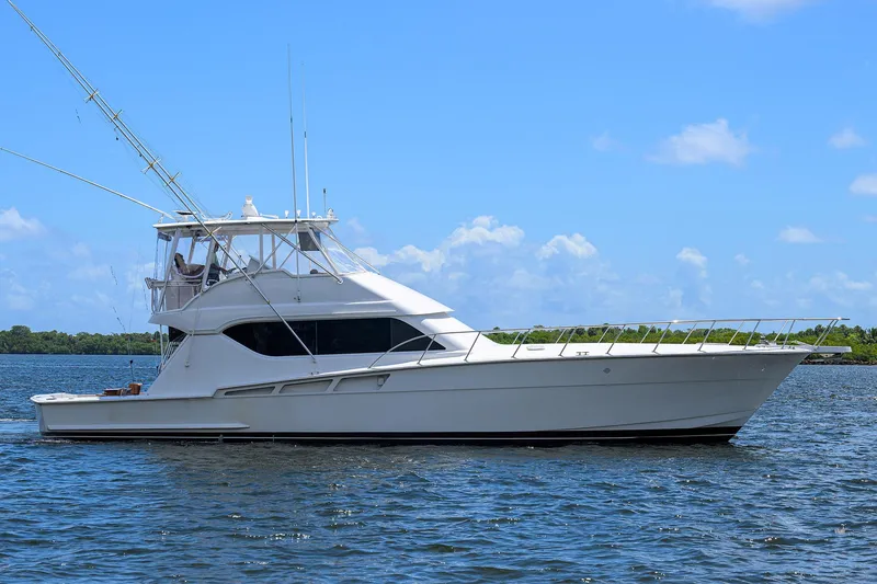 The Image of 2001 Hatteras 60 Convertible yacht on calm water under blue sky. - 0