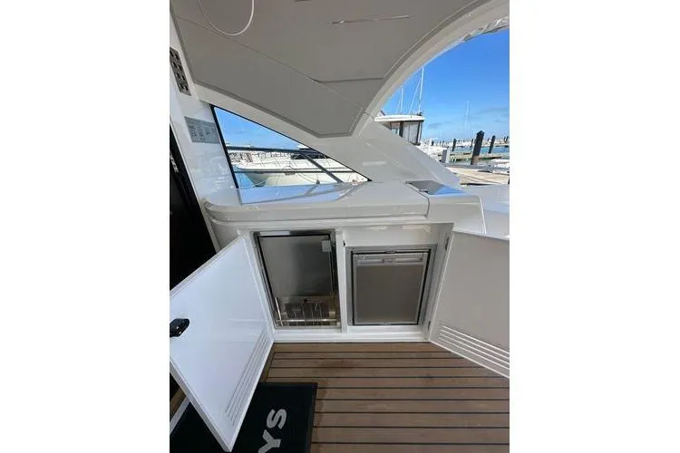 Slide: The Image of 2021 Sunseeker Predator 60 EVO yacht interior with open mini fridge, dock view. - 17