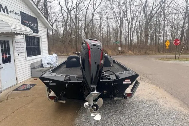 Slide: The Image of 2012 Lowe Stinger 18 HP boat with outboard motor, parked near a marine shop. - 4
