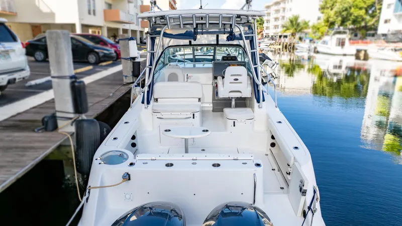 Slide: The Image of 2010 Robalo R305 Walkaround boat docked in a marina, showcasing spacious deck and seating. - 10