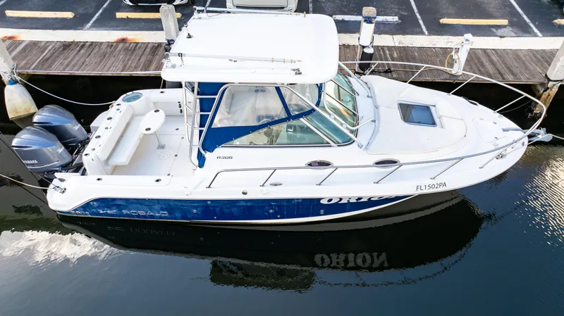 Slide: The Image of 2010 Robalo R305 Walkaround boat docked, featuring dual engines and a spacious deck. - 12