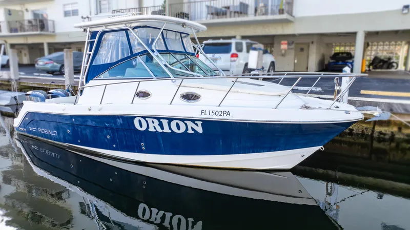 Slide: The Image of 2010 Robalo R305 Walkaround boat named Orion docked in marina. - 13