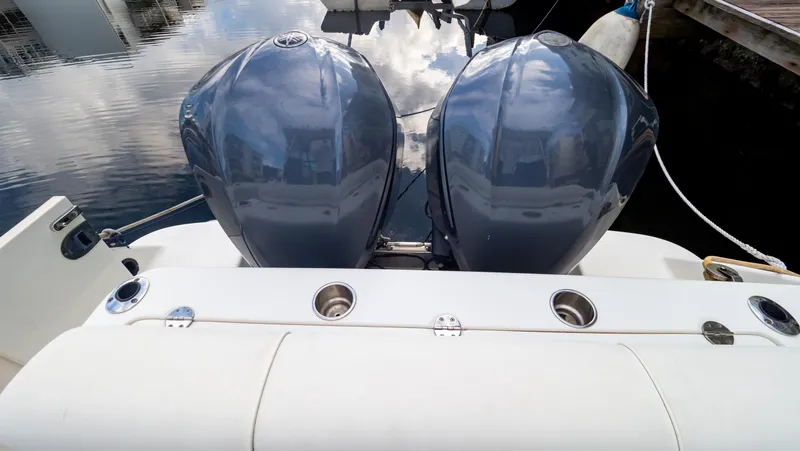 Slide: The Image of 2010 Robalo R305 Walkaround boat with dual outboard engines, docked on calm water. - 17