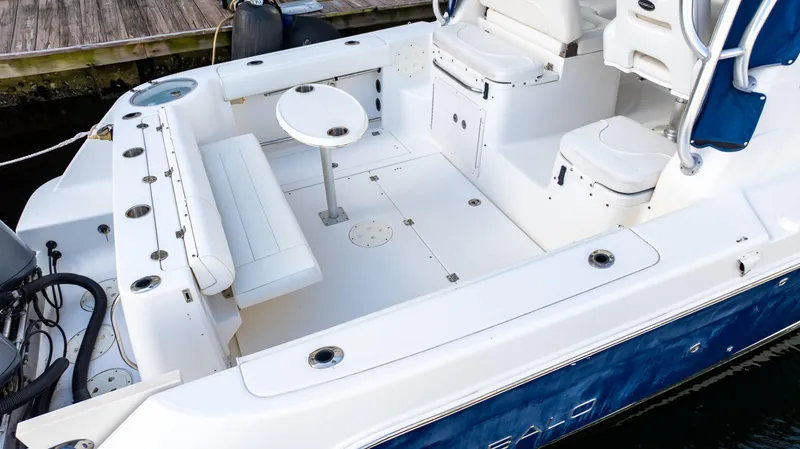 Slide: The Image of 2010 Robalo R305 Walkaround boat deck with seating and table, docked by wooden pier. - 5
