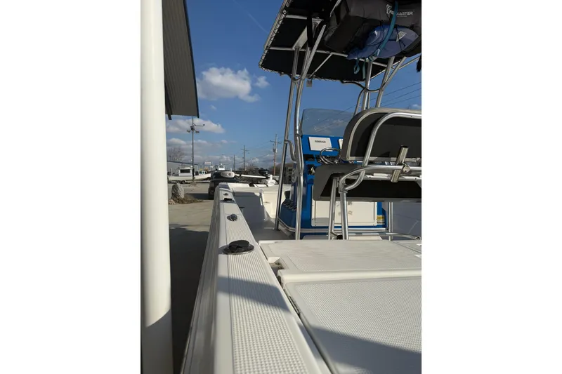 Slide: The Image of 2020 Aquasport 224 Bay boat, side view with seating and console, under clear sky. - 11