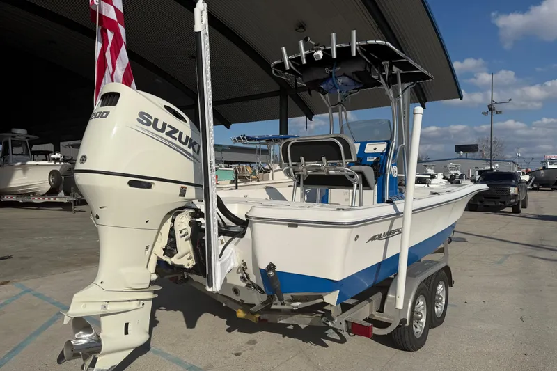 Slide: The Image of 2020 Aquasport 224 Bay boat with Suzuki engine on trailer, parked outdoors. - 3