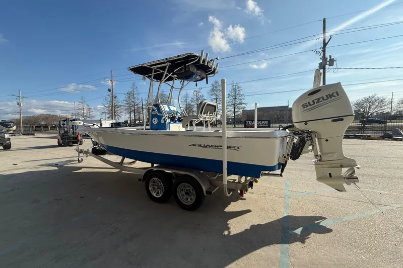 Slide: The Image of 2020 Aquasport 224 Bay boat with Suzuki outboard motor on trailer, parked outdoors. - 5