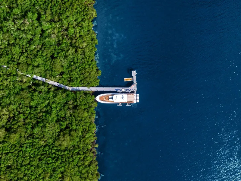Slide: The Image of Aerial view of HCB 65 Estrella yacht docked, surrounded by forest and water. - 11