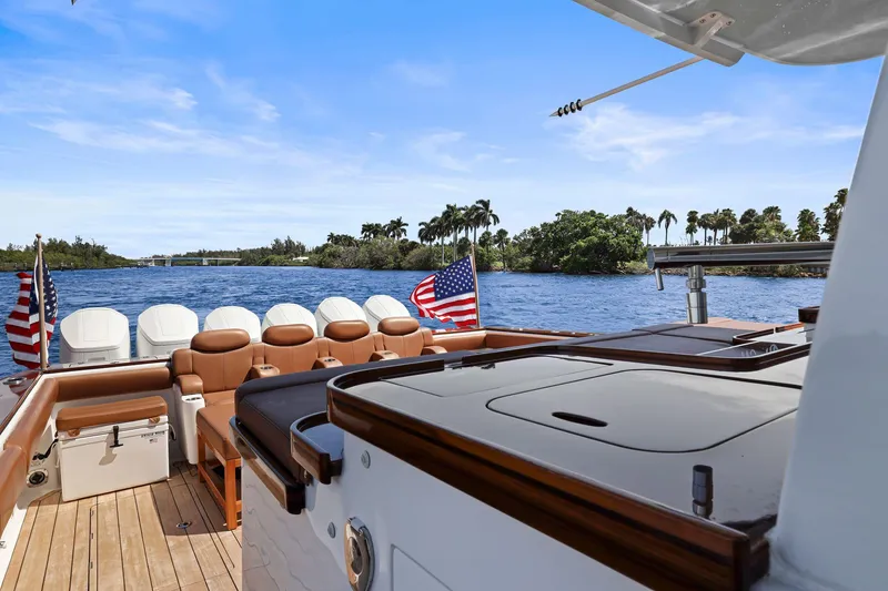 Slide: The Image of 2023 HCB 65 Estrella yacht deck with American flags, luxurious seating, and scenic water view. - 32