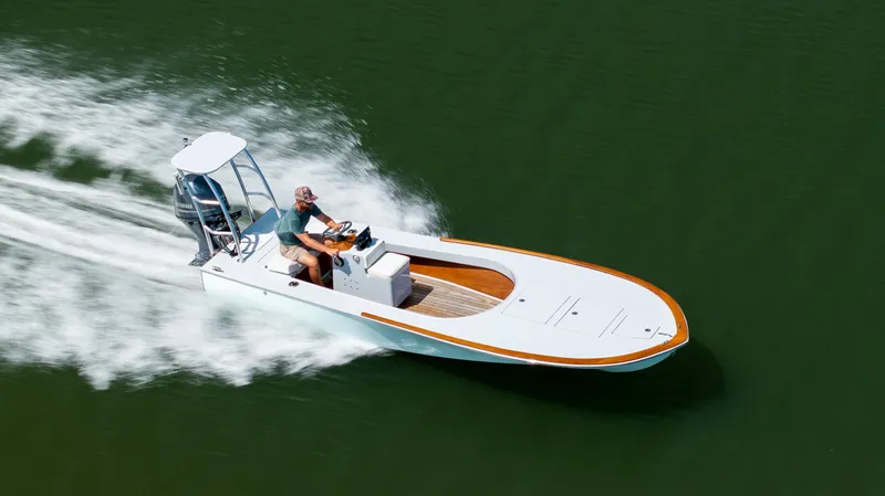 The Image of 2023 Custom Carolina 18 Flats boat speeding on water, showcasing sleek design and performance. - 0