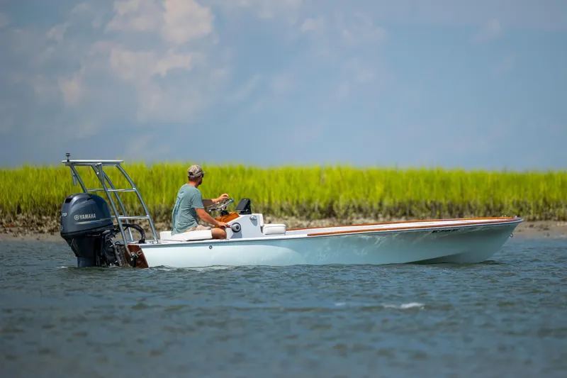 Slide: The Image of 2023 Custom Carolina 18 Flats boat on water with Yamaha engine, near grassy shoreline. - 15