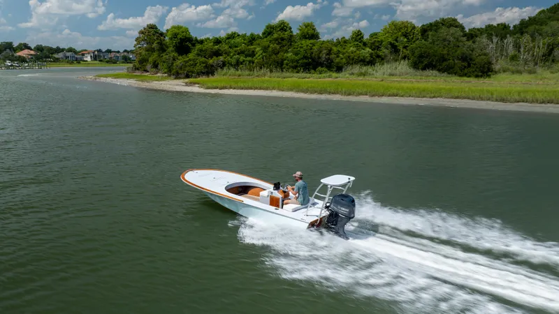 Slide: The Image of 2023 Custom Carolina 18 Flats boat cruising on a scenic waterway. - 4
