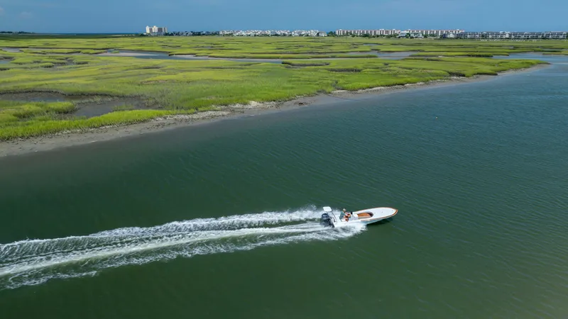 Slide: The Image of Aerial view of 2023 Custom Carolina 18 Flats boat cruising through coastal waters. - 6